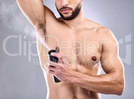 I want to smell good. Studio shot of a young man spraying deodorant on his armpit.