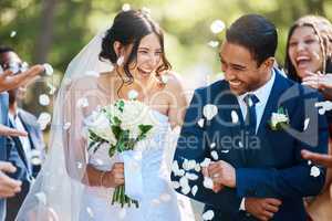 Guests throwing confetti over bride and groom as they walk past after their wedding ceremony. Joyful young couple celebrating their wedding day