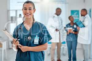 Portrait of a mixed race female doctor holding a clipboard working at a hospital with colleagues. Hispanic expert medical professional smiling ready for work at a clinic with coworkers