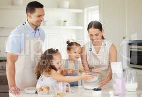 Everyone can lend a hand. a young family baking together at home.