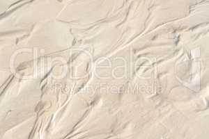 Abstract white sand sediment pattern, seaside natural organic landscape shining in the sun. Top view of a conceptual textured image of moist sea sand formed at the sea shore on a summer vacation.