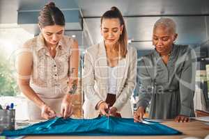 Designers are like magicians for fashion. a group of young female designers cutting material at a boutique.