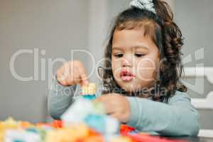 She likes creating things. Shot of a cute little girl playing with building blocks at the kitchen table.