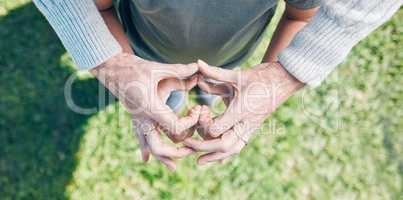 Nurturing with love. an unrecognizable little boy and his grandmother holding their hands together in a heart shape outside.