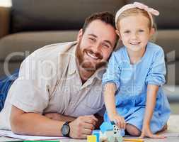 Portrait of father and daughter bonding at home. Dad watching daughter play with toys. Parent and child smiling happy to be together