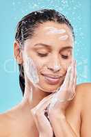 My skin loves the moisture. Shot of a young woman washing her face against a blue background.