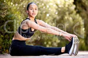 One fit young mixed race woman touching feet to stretch legs for warmup to prevent injury while exercising outdoors. Hispanic athlete staying motivated and determined while mentally and physically preparing for training workout