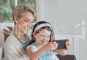 Trying filters with grandma. Shot of a mature woman taking a selfie with her granddaughter at home.