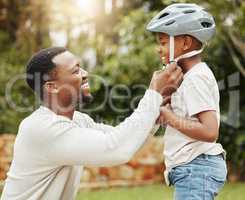 Protecting his baby. a father adjusting his sons helmet outside.