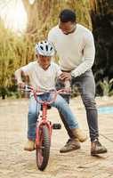 Taste of freedom. an adorable boy learning to ride a bicycle with his father outdoors.