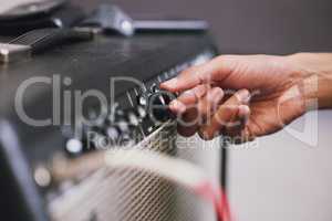 Lets find the right tone. an unrecognisable man using an amplifier in a music studio during the day.