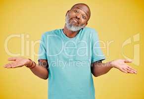 Portrait of a mature african american man smiling and making a gesture of not knowing something while smiling against a yellow studio background. Black african man looking quirky. Sometimes you dont know what surprises might be waiting for you
