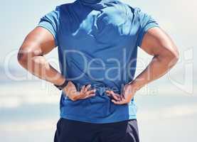 I feel the pain in my back. Shot of a man experiencing discomfort in his back while out for a workout.