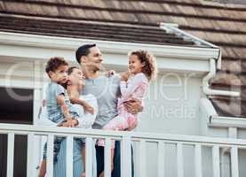 Happy young mixed race family with two children standing outside on their balcony at home. Loving couple with their daughter and son wearing pyjamas and enjoying their new house