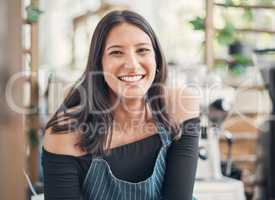 Portrait of one happy young hispanic waitress working in a store or cafe. Friendly woman and coffeeshop owner managing a successful restaurant startup