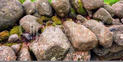 Closeup of many big rocks covered in lichen. Landscape of green moss contrasting on pile of weathered stones in the wild or uncultivated environment. Beautiful details of rough rocky nature textures