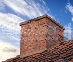Closeup of red brick chimney chute against blue sky with clouds for combustion gas or home insulation on tiled roof. Architecture design on house building for smoke extraction from fireplace furnace