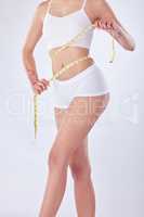 A gift of femininity. Studio shot of an unrecognizable woman measuring her waist against a white background.