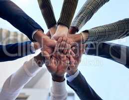 A supportive team is the best team. a group of unrecognizable businesspeople stacking their hands outside.
