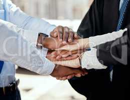 We can achieve anything together. a group of unrecognizable businesspeople stacking their hands in the city.