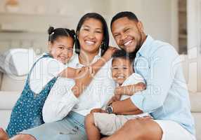 Life begins with family and ends with family. a young family happily bonding together on the sofa at home.