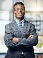 Happy to be of service. a young male lawyer standing with his arms crossed at work.