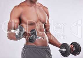 Form is not forever, you need to maintain it. Studio shot of a muscular young man exercising with a dumbbell against a grey background.