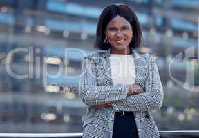 Shes an expert at all things business. a mature businesswoman standing with her arms crossed against a city background.