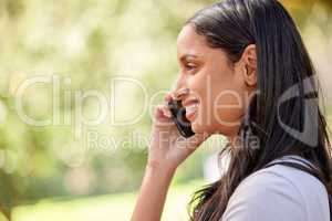 Call me. an attractive young woman making a phonecall while standing outside.