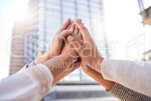 Believe in your power to achieve great things. a group of unrecognizable businesspeople giving each other a high five against a city background.