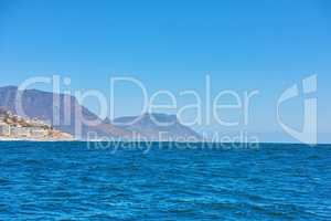 The deep blue sea or vast expanse of the open ocean under clear blue sky copy space with Table Mountain in the background. Calm waters on a picturesque summer morning and view of the horizon