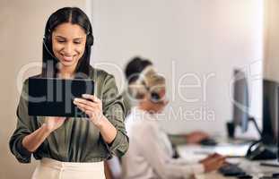 Im finding exactly what I need. a young call centre agent using a digital tablet while working in an office with her colleagues in the background.