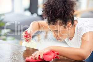 No fear and no mercy. a young woman cleaning her living room coffee table.