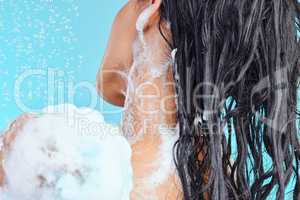 I am a woman comfortable in her own skin. a beautiful young woman enjoying a soapy shower against a blue background.