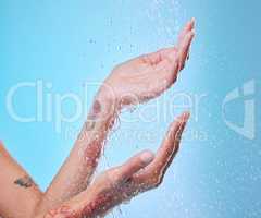 Let the water wash your troubles away. Studio shot of an unrecognizable young woman showering against a blue background.