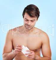 The best product on the market. a young man holding a bottle of lotion against a studio background.