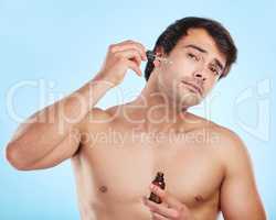 Paving the road to fabulous skin. a handsome young man applying a serum to his skin against a studio background.