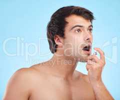 Not a frog but a prince. a young man using mouth spray against a studio background.