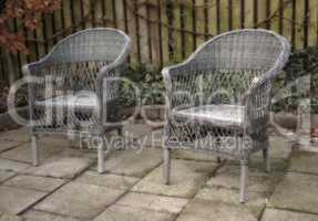 Garden chairs on a patio in a backyard garden in summer. Old, rustic, and vintage garden furniture is used for relaxation and sitting while relaxing out in nature. Peaceful and quiet area in a yard