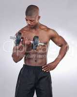 Bigger arms are the goal. a handsome man standing alone in the studio and using a dumbbell to workout.
