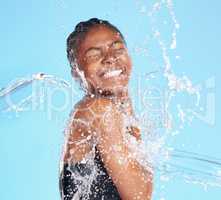 She knows how to have fun. a beautiful young woman being splashed with water against a blue background.