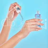 Stay young. Studio shot of an unrecognizable woman applyng antiaging serum to her hands against a blue background.