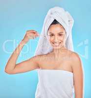 After shower treatment. Studio portrait of an attractive young woman applyng antiaging serum to her face against a blue background.