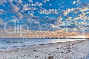 Seascape view of nature on the coast of a beach, and ocean water on a sunny summer day. Beautiful scenery of a sea shore filled with sand and a cloudy blue sky over the horizon with tide and current