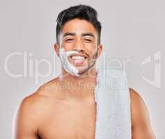 Are you ready for the transformation. a young man shaving his beard against a grey background.