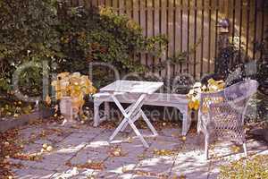 Cozy garden area for coffee and reading. Old wooden and forgotten furniture in a stone patio outdoors with copy space. Private location to relax and enjoy alone time in warm summer weather outside