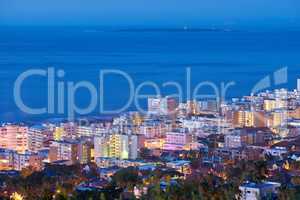 Beautiful sunset sky over a cityscape view as seen from Signal Hill in Cape Town, South Africa. Scenic panoramic landscape of lights illuminating an urban metropolitan skyline along the sea