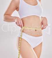 Start making healthy choices, your body will thank you later. Studio shot of a fit young woman holding a measuring tape around her waist.