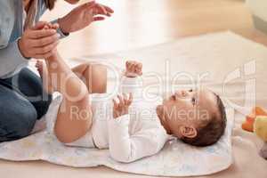 Routine is the route to a secure and happy baby. a woman changing her adorable baby girls diaper at home.
