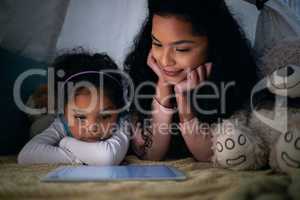 Look what I found Mom. a little girl and her mother watching something on a digital tablet at night.